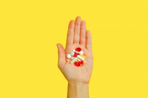 Hand full of Nurofen tablets with a yellow background